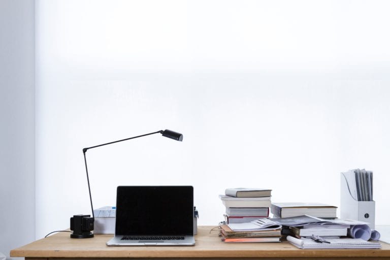 Case study interview examples, insead case book, darden case studies, wharton consulting club casebook. Image shows a picture of a desk piled high with textbooks and paperwork.