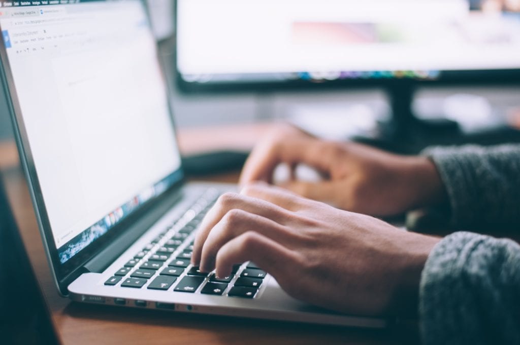 management consulting cover letters & tips. This image depicts two hands typing at a laptop computer.